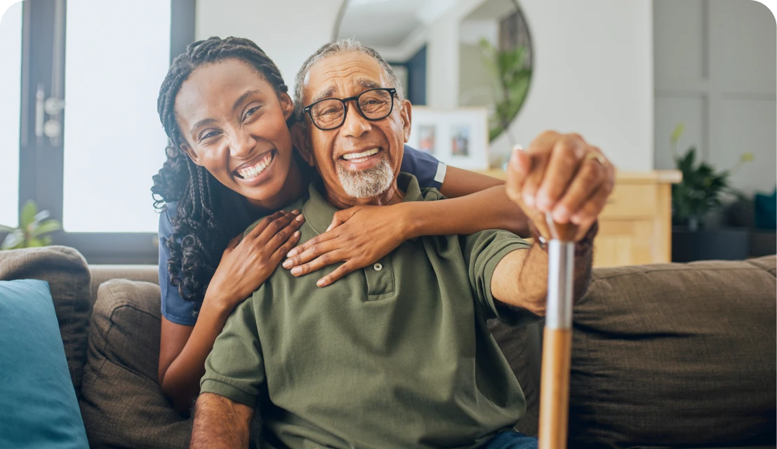 Smiling woman hugging elderly man on sofa