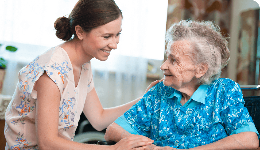 Young woman comforting elderly woman in wheelchair.